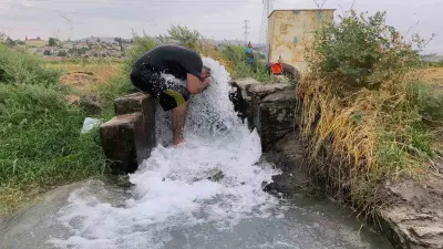 Kavurucu sıcakta elbisesini bile çıkarmadan buz gibi sondaj suyunda serinledi